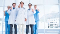 Group portrait of young doctors gesturing thumbs up at hospital